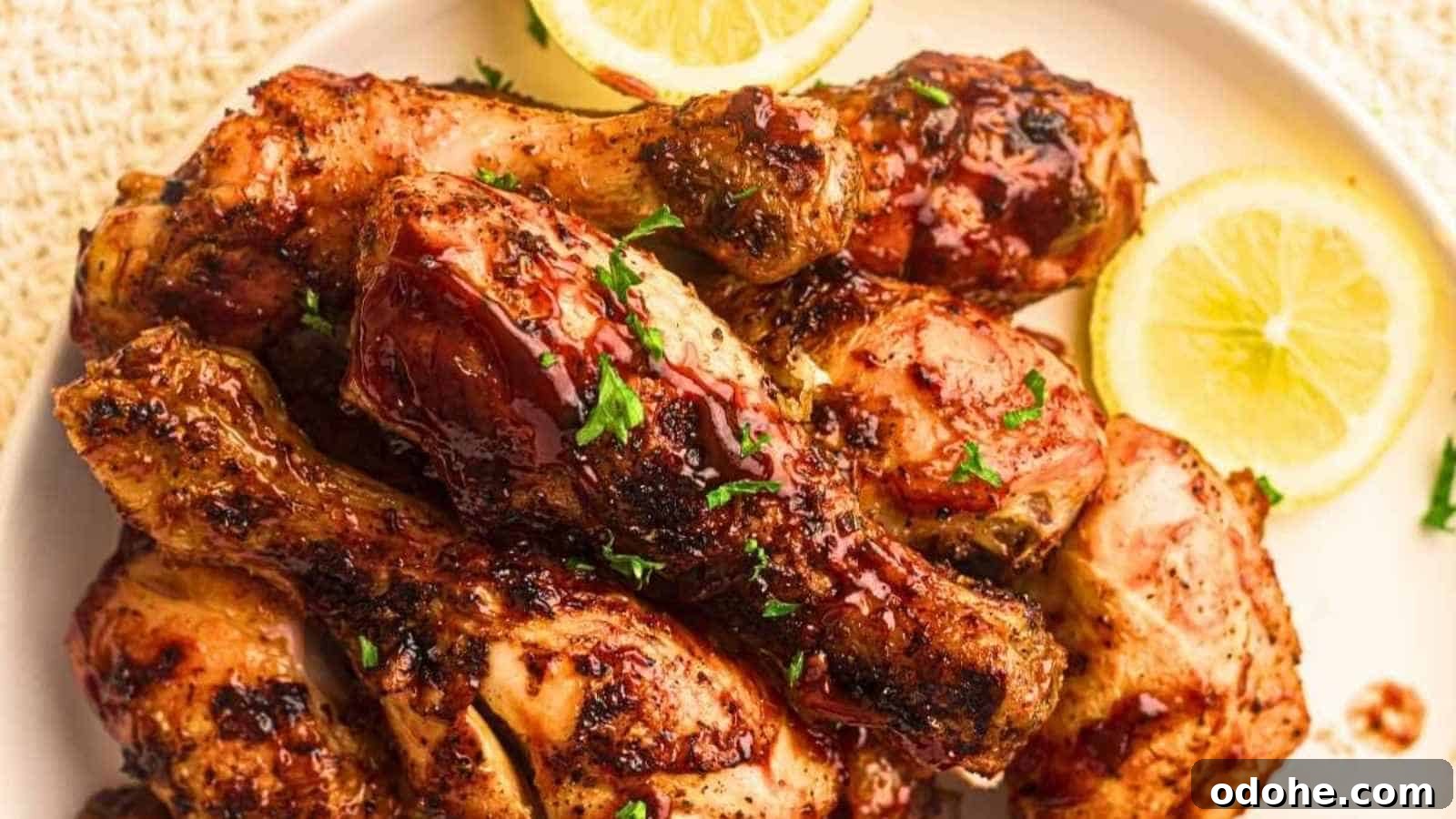 31 Memorial Day Recipes to Start Cookout Season Right 18 A plate of grilled chicken drumsticks garnished with chopped herbs, served with lemon slices.
