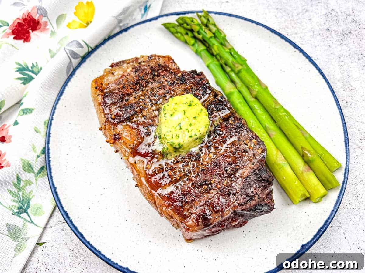 31 Memorial Day Recipes to Start Cookout Season Right 29 Reverse Seared Smoked Steaks with Smoked Garlic Butter on a plate with asparagus.