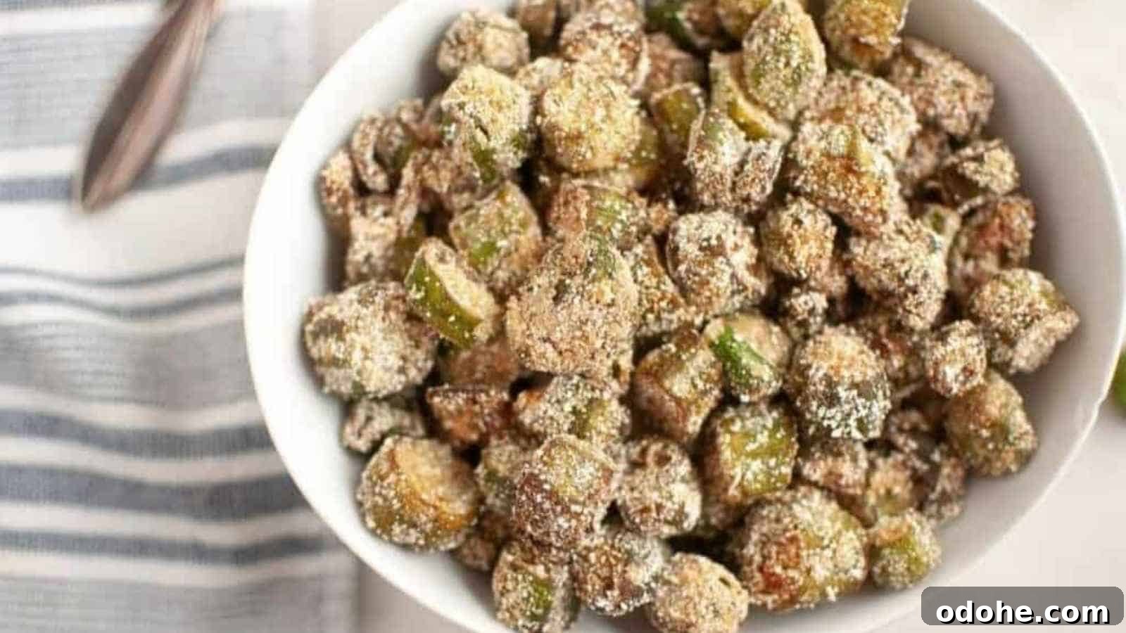 31 Memorial Day Recipes to Start Cookout Season Right 4 A white bowl filled with crispy, breaded and fried okra pieces, placed on a light surface next to a striped cloth napkin.