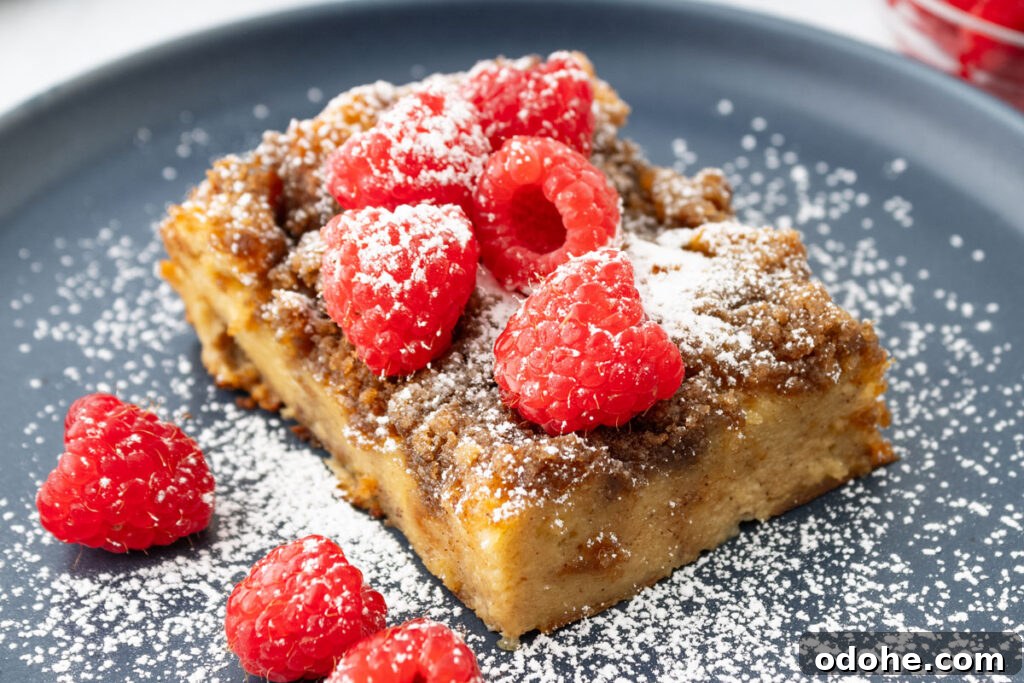 piece of French toast casserole with raspberries and powdered sugar on grey plate