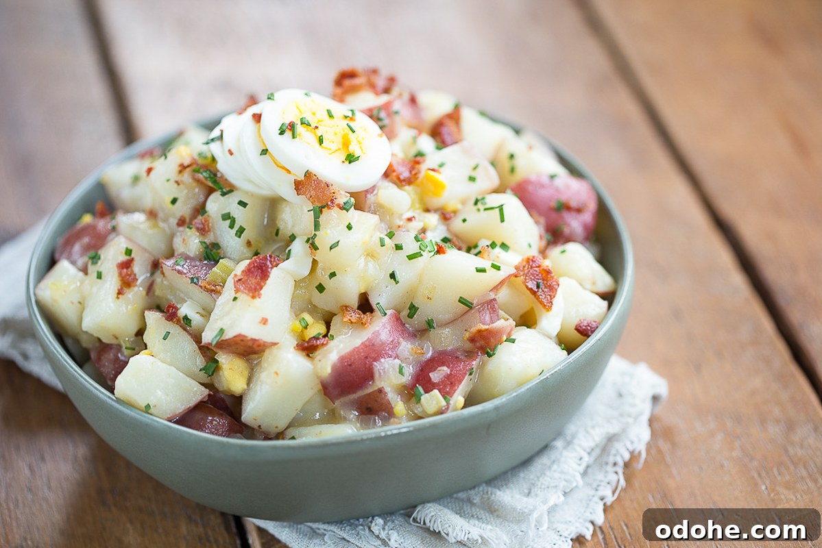 Authentic German Potato Salad with Hard-Boiled Eggs & Bacon 11 German potato salad in a green bowl on a wood table