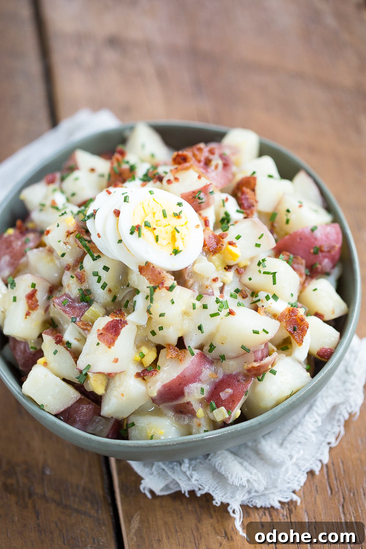 Authentic German Potato Salad with Hard-Boiled Eggs & Bacon 12 german potato salad with eggs in a green bowl.