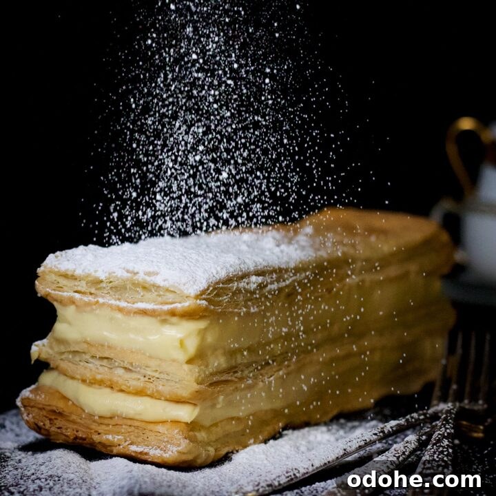 Sprinkling powdered sugar over the top of a classic French Napoleon right before serving.