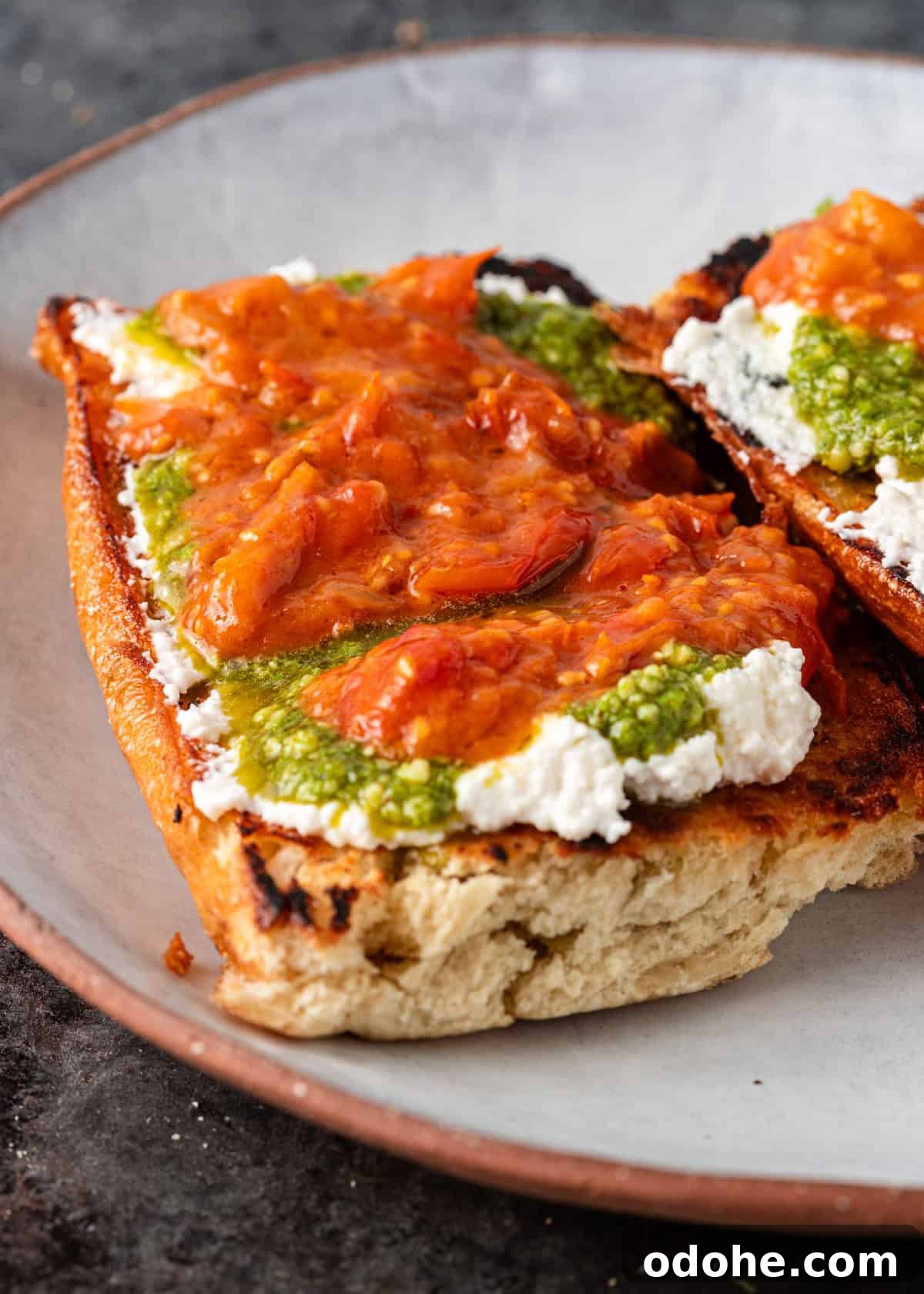 Slow-Roasted Cherry Tomato Confit Recipe for Flavorful Dishes 11 closeup: toasted bread with cheese, pesto, and tomato garlic confit