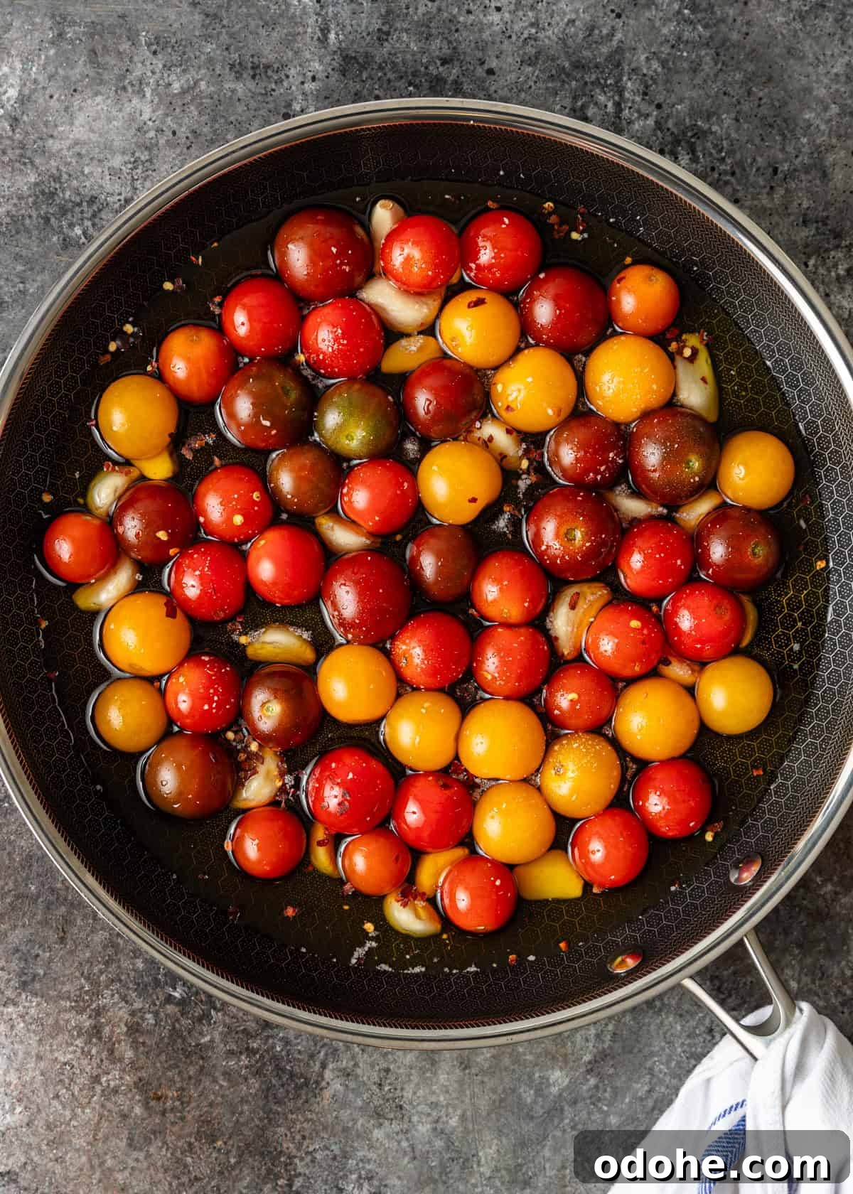 Slow-Roasted Cherry Tomato Confit Recipe for Flavorful Dishes 5 overhead process shot: cherry tomatoes in a skillet with oil and garlic