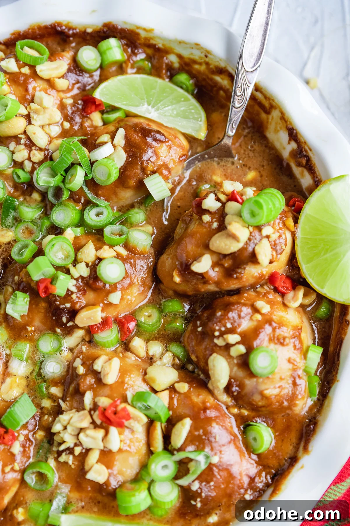 Spicy Thai Peanut Chicken Thighs with Sticky Glaze 6 A close up of part of a dish of spicy peanut butter chicken from above with a serving spoon