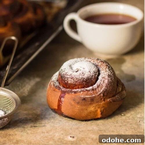 A cinnamon roll placed near a cup of coffee.