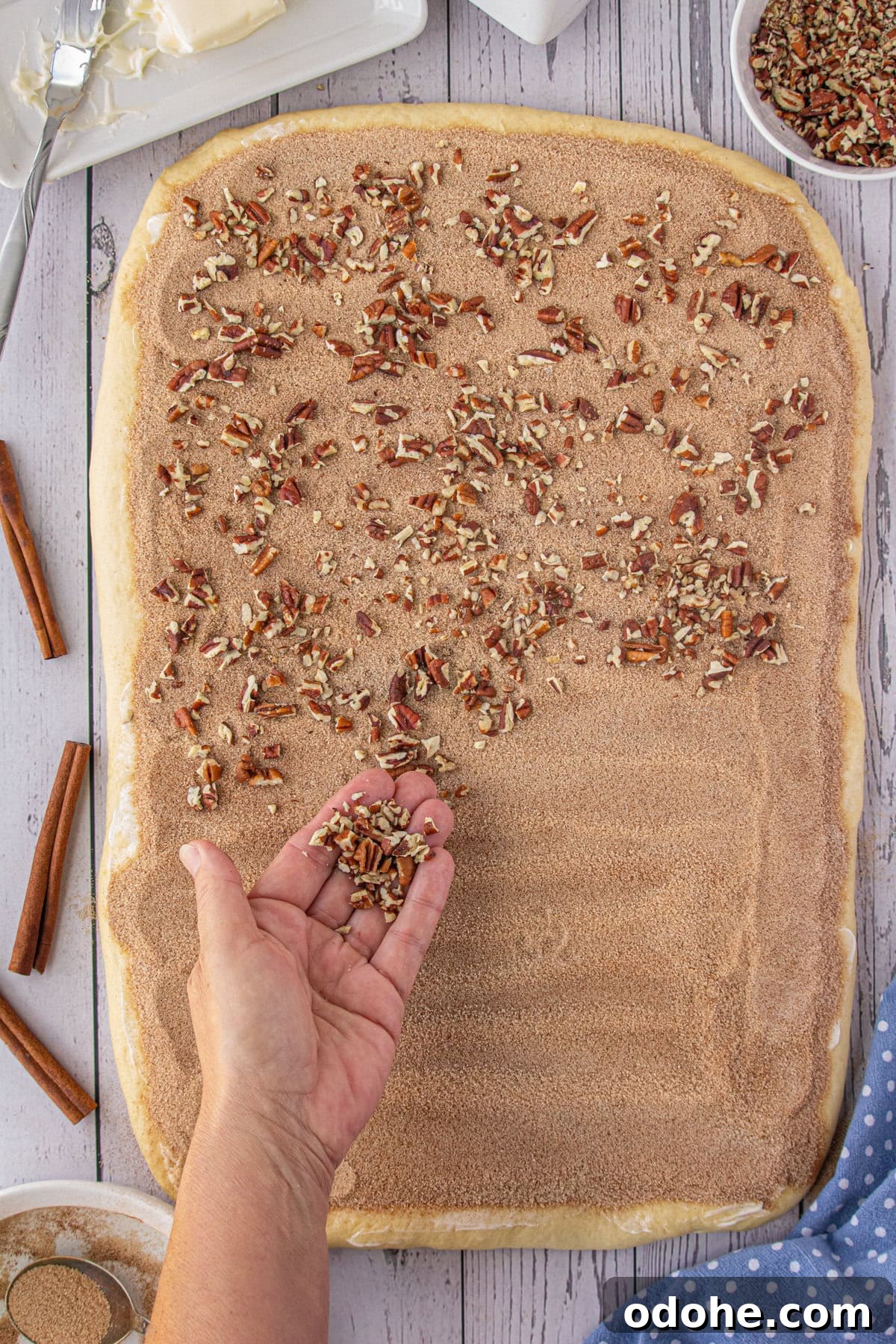 Giant Texas-Style Cinnamon Rolls: Soft, Gooey, Oversized Treat 9 Pecans being added over the cinnamon.