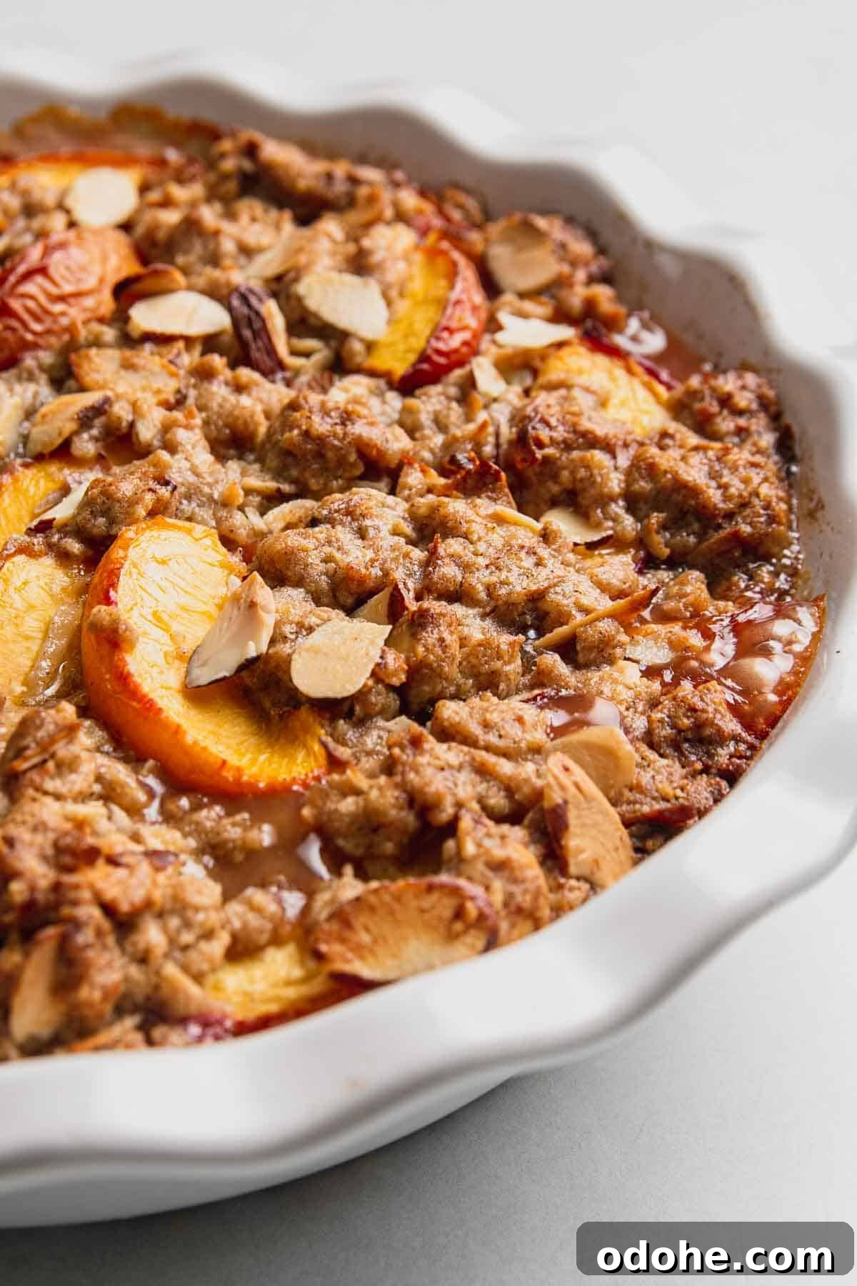 Gluten-Free Peach Crisp with Oats & Almonds — Simple Summer Dessert 6 Bubbly peach crisp in white pie dish.