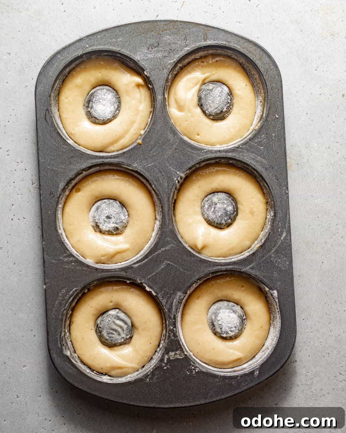 Powdered Sugar Donuts Recipe: Light, Fluffy Homemade Donuts 7 donut batter piped into a donut pan.
