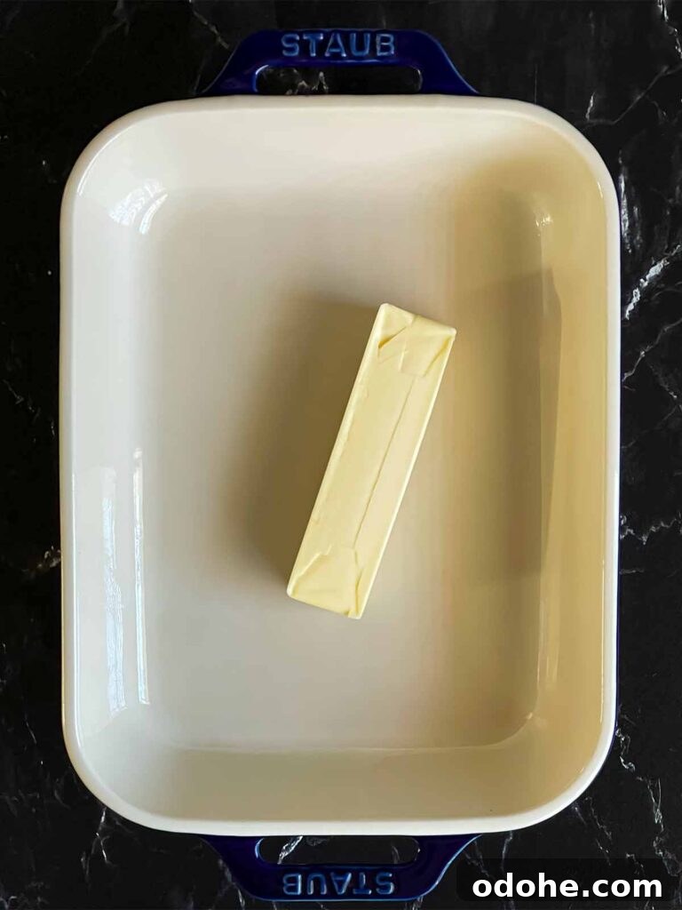 A stick of butter in a casserole dish.