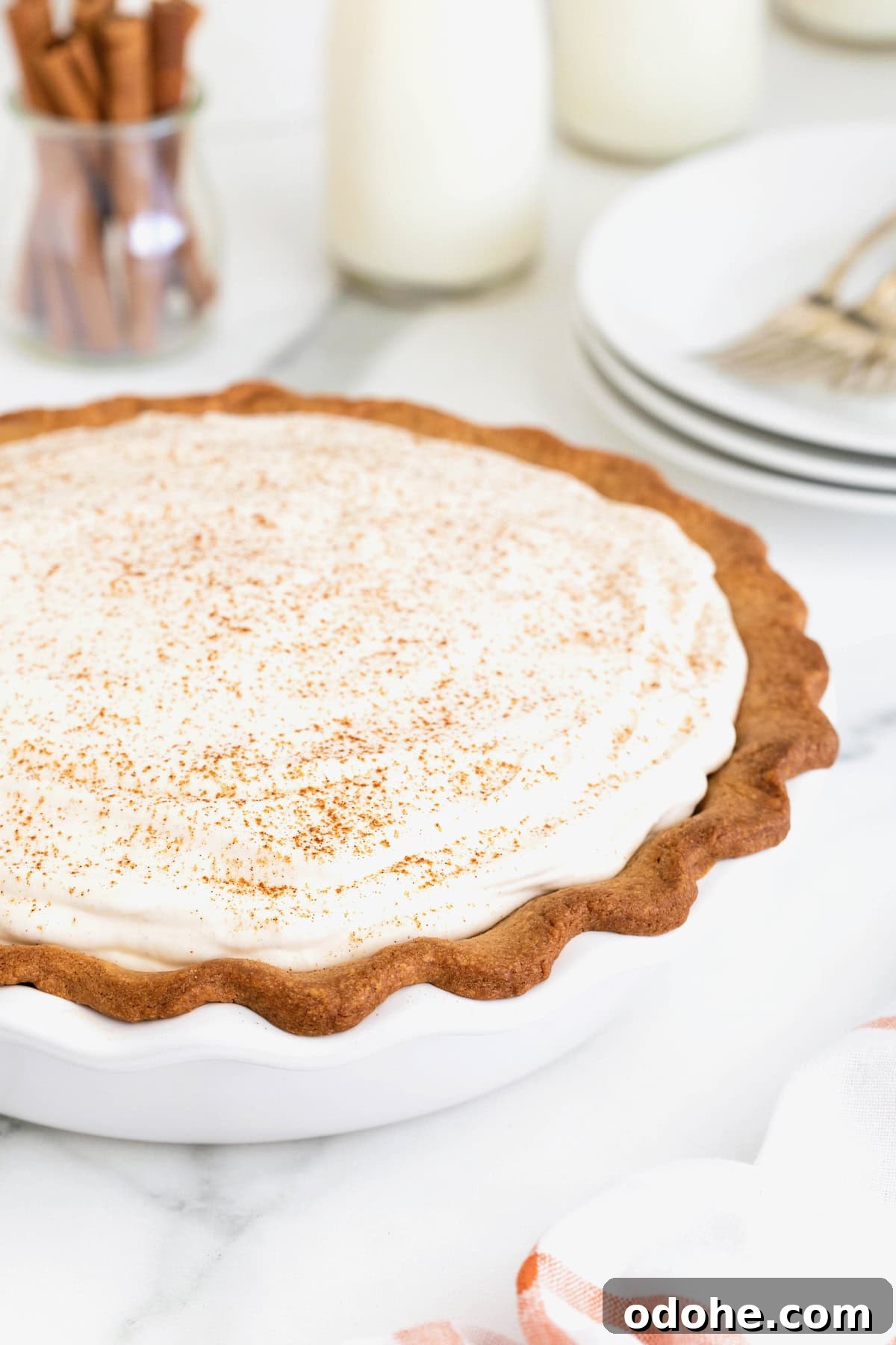 Creamy Pumpkin Pie Recipe: Classic Autumn Dessert Guide 14 A pumpkin cream pie in a white milk glass pie plate on a white marble counter.