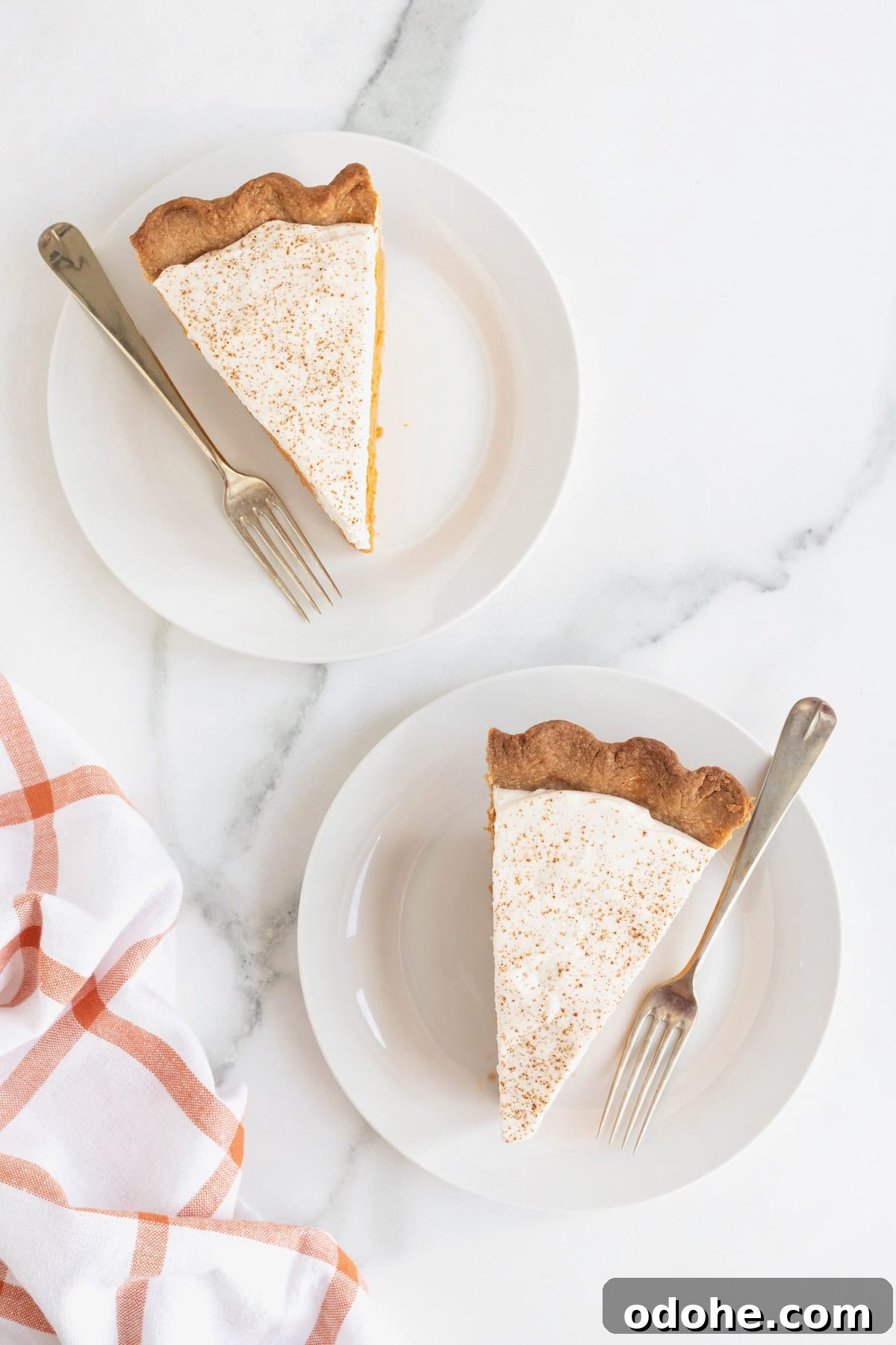 Creamy Pumpkin Pie Recipe: Classic Autumn Dessert Guide 4 Two slices of pumpkin cream pie on small white dessert plates. There are silver tone forks beside the pie pieces.