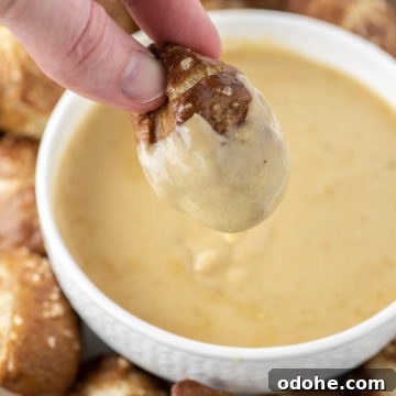 pretzel bite being dipped in beer cheese dip