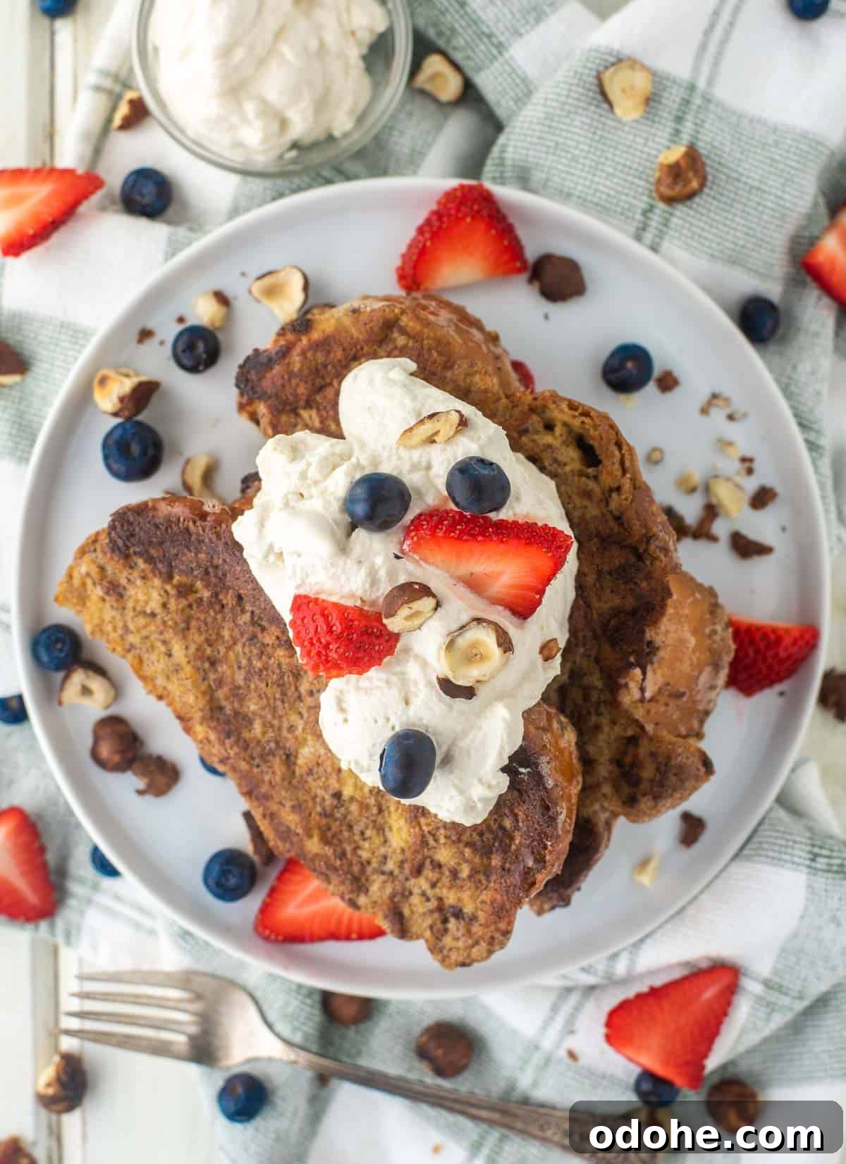 Baileys-Infused French Toast Recipe for Adults 3 Baileys French toast on white plate with whipped cream and fruit.