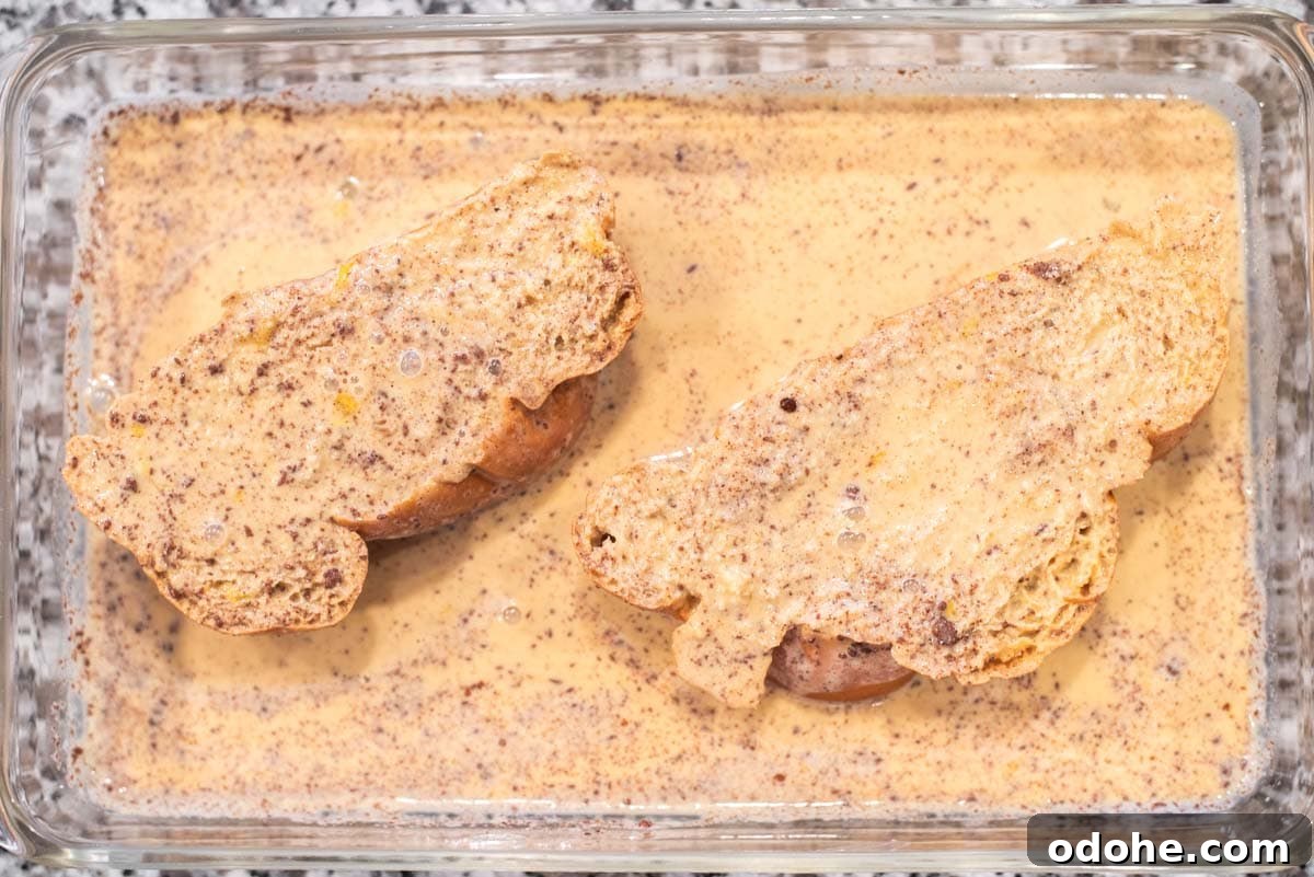 Baileys-Infused French Toast Recipe for Adults 5 Bread dipped in custard in glass pan.