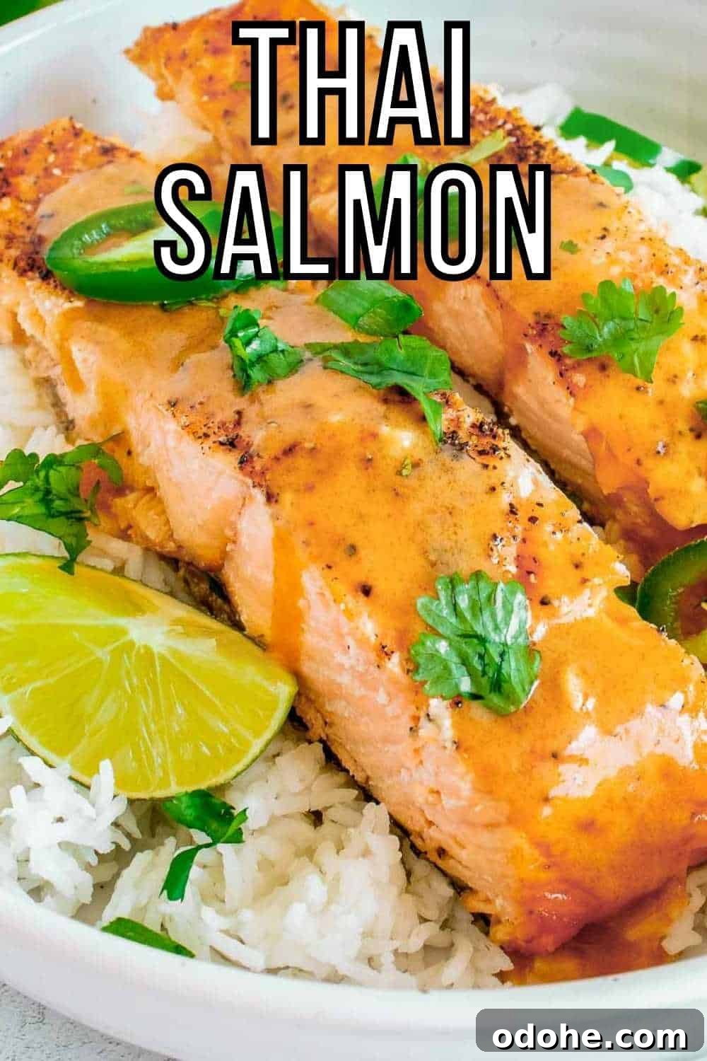 Thai-Style Salmon with Coconut Lime Sauce 2 Side close up shot of two pieces of salmon on a bed of rice garnished with parsley and cut jalapeños in a large white bowl with lime wedges on the side.