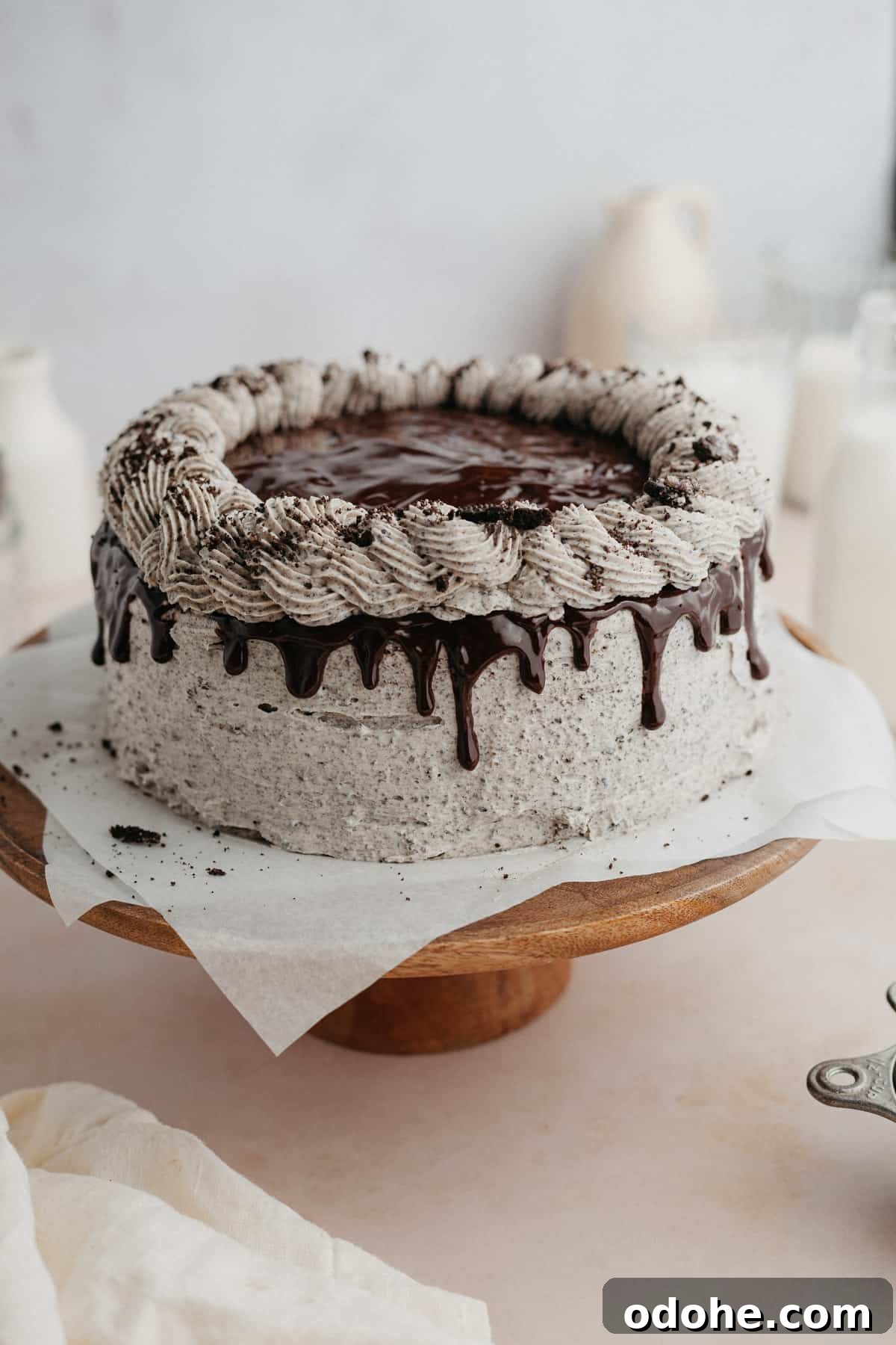 An oreo drip cake on a wooden cake stand