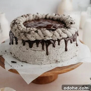 An oreo drip cake on a wooden cake stand