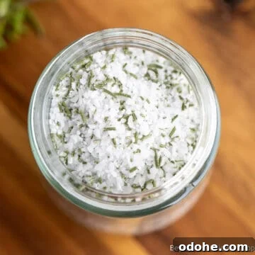 A jar filled with coarse salt and dried rosemary.