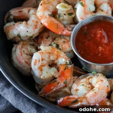 Garlic cocktail shrimp in a bowl with cocktail sauce.