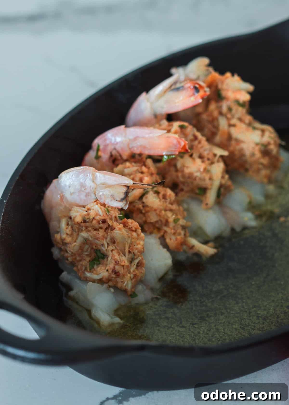 Stuffed shrimp in baking dish coated with melted butter.