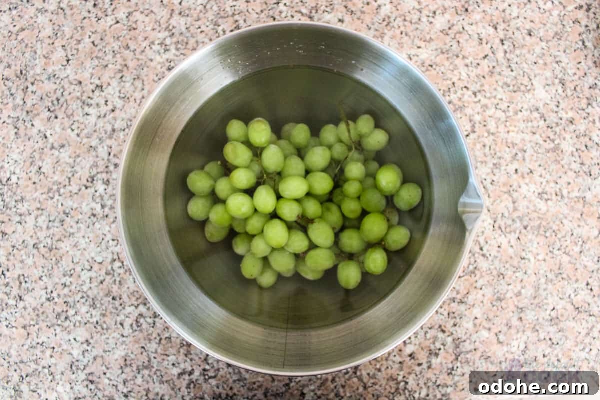 A bowl sitting on a kitchen counter filled with green grapes covered with water and vinegar.