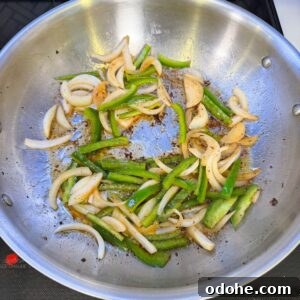 Onions and peppers cooking in a pan.