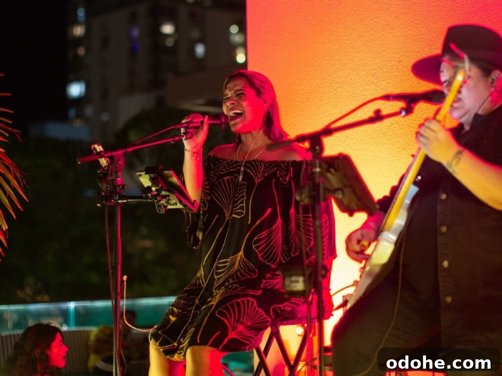 Two people performing live music under orange and red lighting at The Hideout, on the lānai (balcony) at The Laylow hotel.