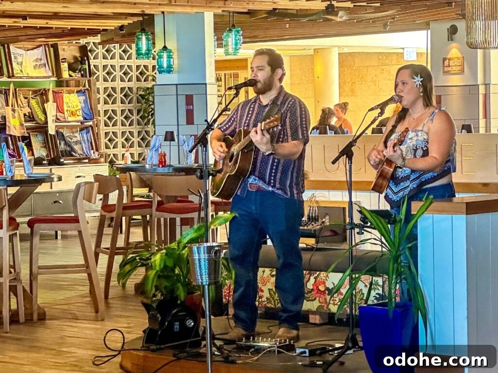 Two musicians performing with guitars at Monkeypod Kitchen in Waikīkī, creating a relaxed and laid-back atmosphere for guests enjoying the live music experience.