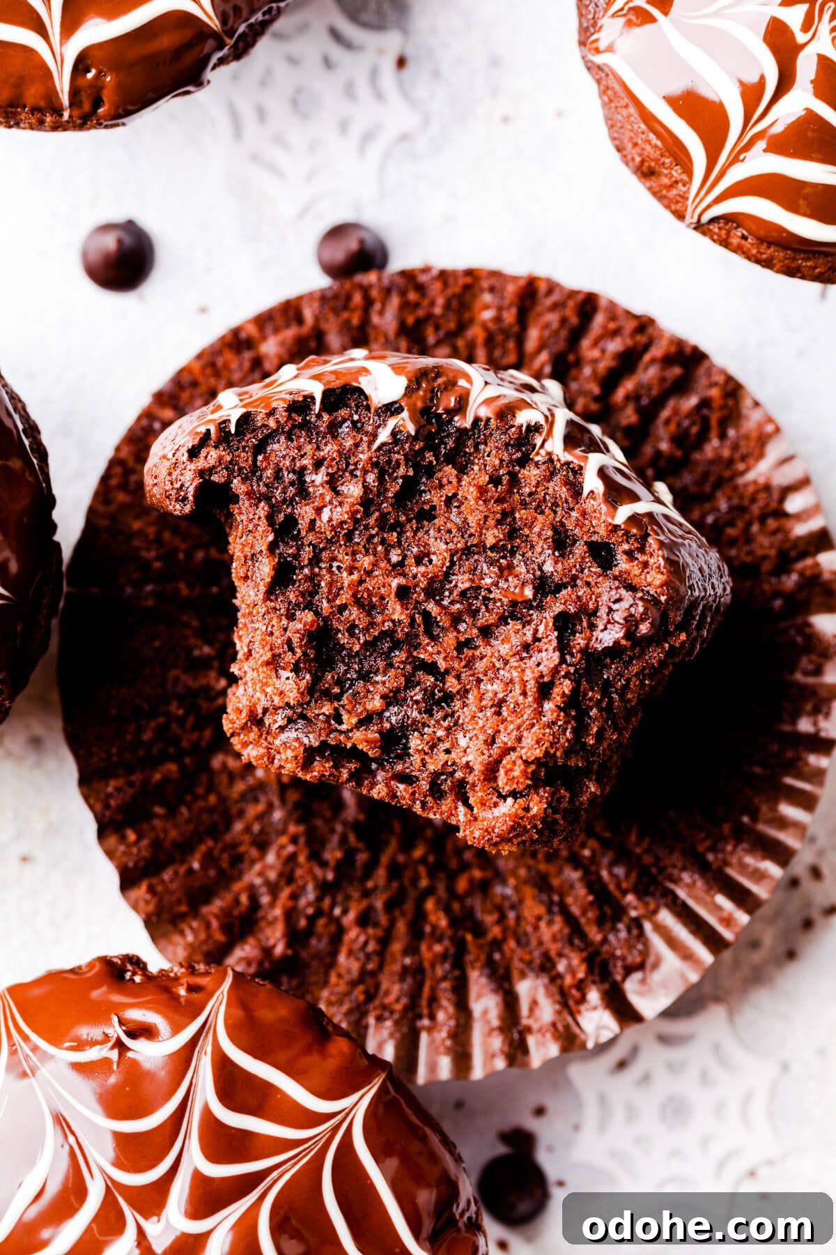 Chocolate Fudge Spiderweb Muffins Recipe — Decadent Halloween Treat 14 an individual chocolate fudge muffin with bite taken out of it.