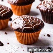 Chocolate Fudge Spiderweb Muffins Recipe — Decadent Halloween Treat 16 a single chocolate fudge spiderweb muffin in a bright orange muffin case.