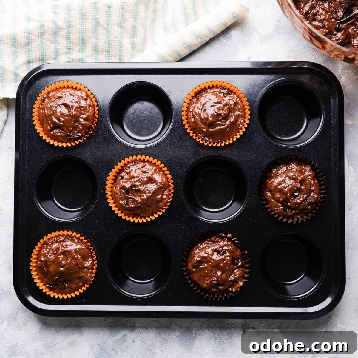Chocolate Fudge Spiderweb Muffins Recipe — Decadent Halloween Treat 7 a muffin tin with 6 paper cases filled with muffin batter.