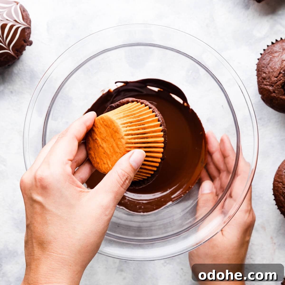 Chocolate Fudge Spiderweb Muffins Recipe — Decadent Halloween Treat 8 pair of hands dipping a chocolate muffin into a bowl with melted chocolate.