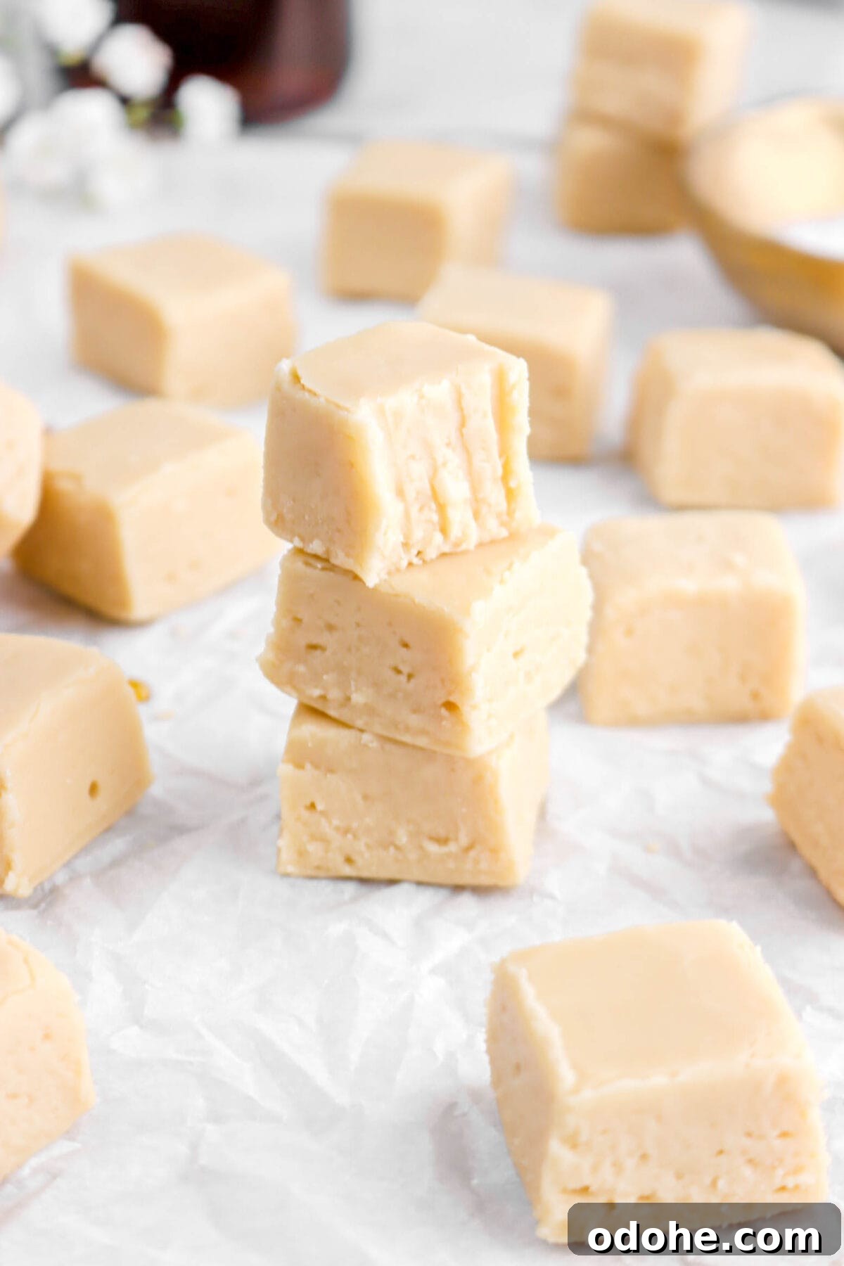 angloed close up of three stacked maple fudge pieces with top piece missing a bite.