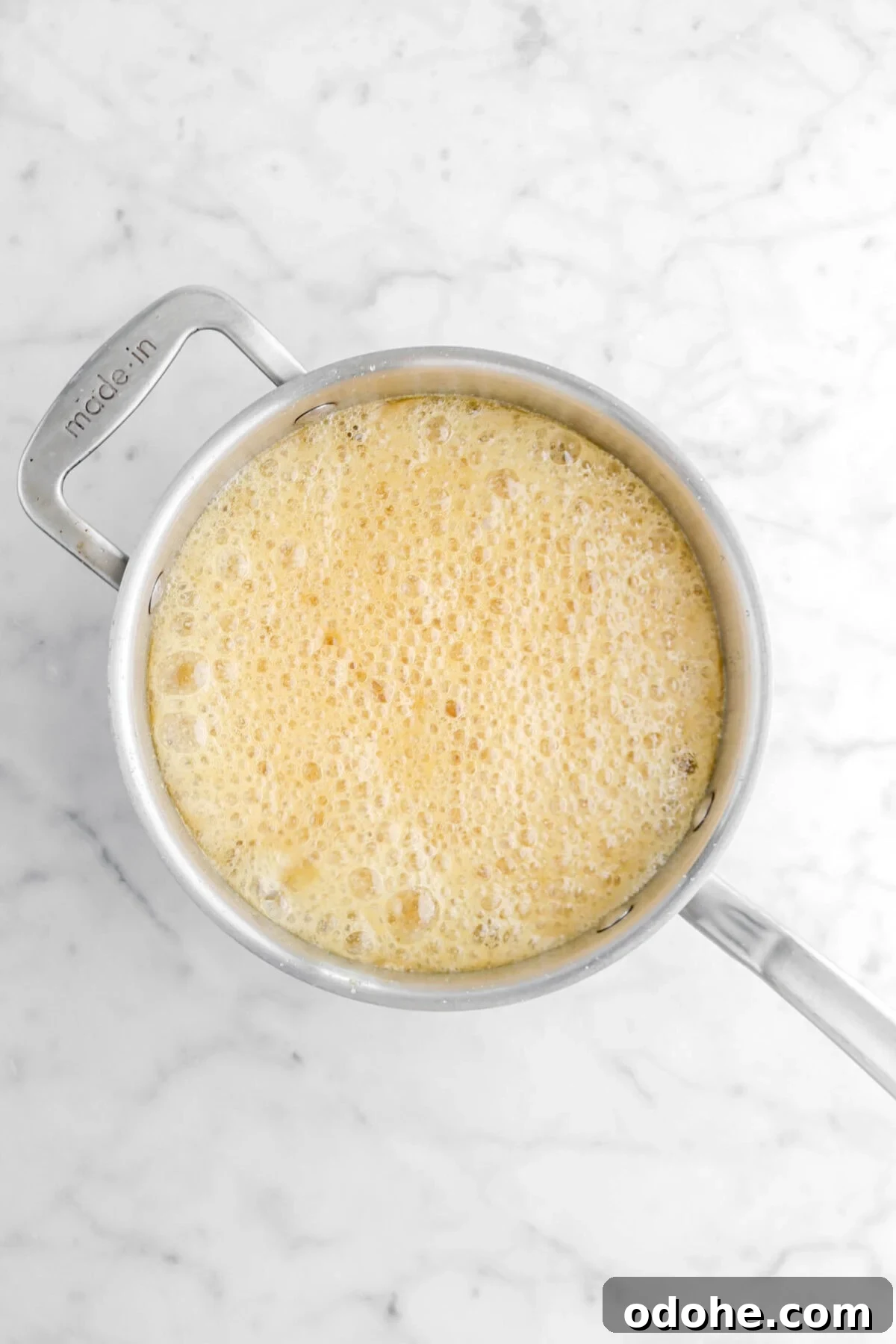 bubbling hot caramel in pot on marble surface.