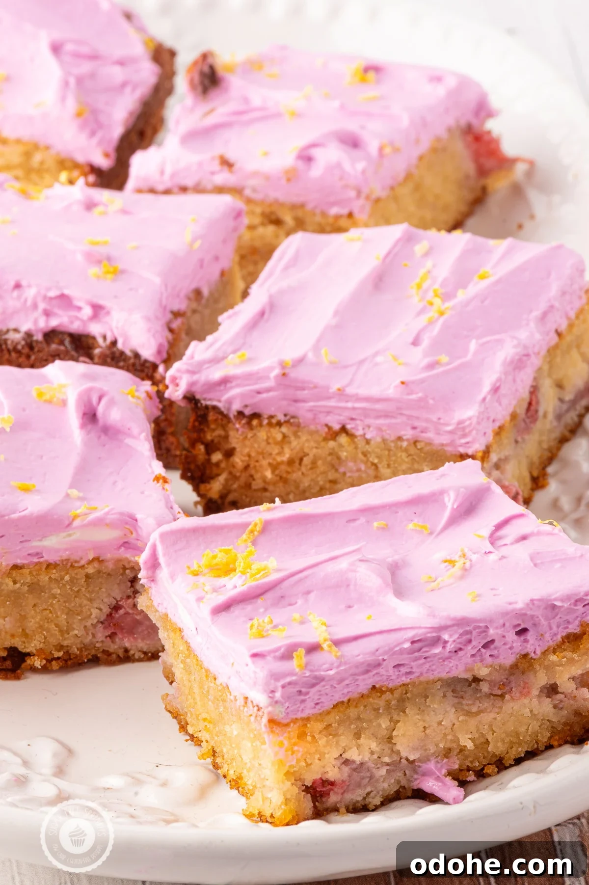 A tray of pink frosted strawberry blondies. 