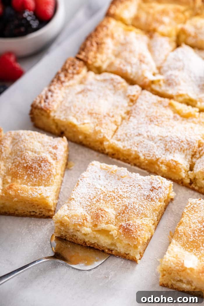 Sliced gooey butter cake, with a cake server about to lift up a slice of the cake.