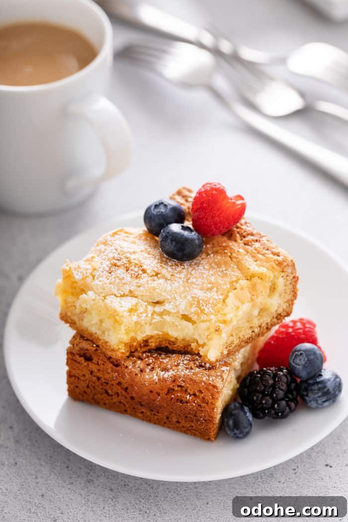 Two pieces of stacked gooey butter cake with a bite taken from the top slice.