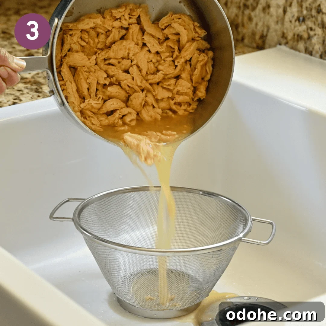 Person dumping the soy curls into a colander to drain the broth.