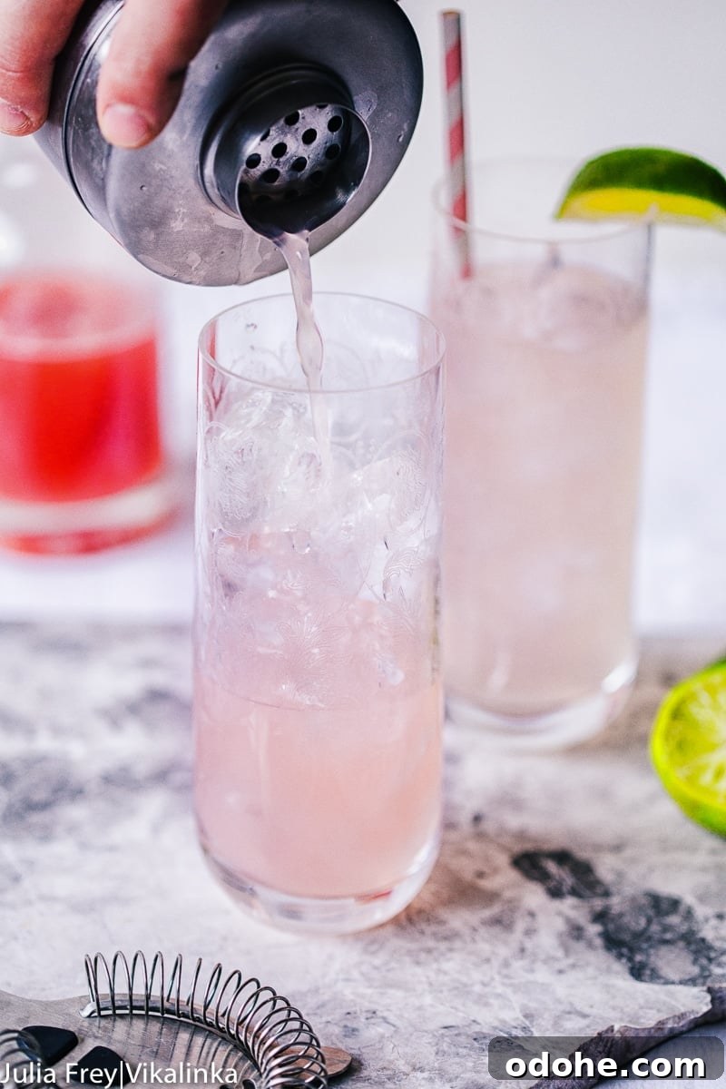 Cocktail shaker pouring drink over ice