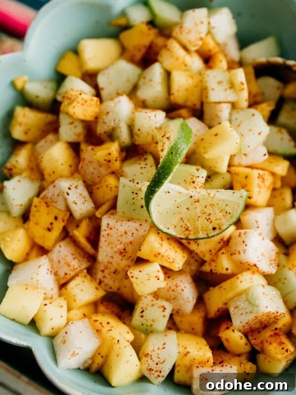 overhead shot of a turquoise bowl filled with mango jicama cucumber salad