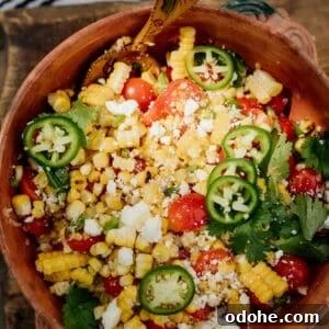 Colorful Mexican Street Corn Salad served in a traditional clay bowl with grilled corn, cherry tomatoes, jalapeño slices, crumbled cotija cheese, and fresh cilantro.