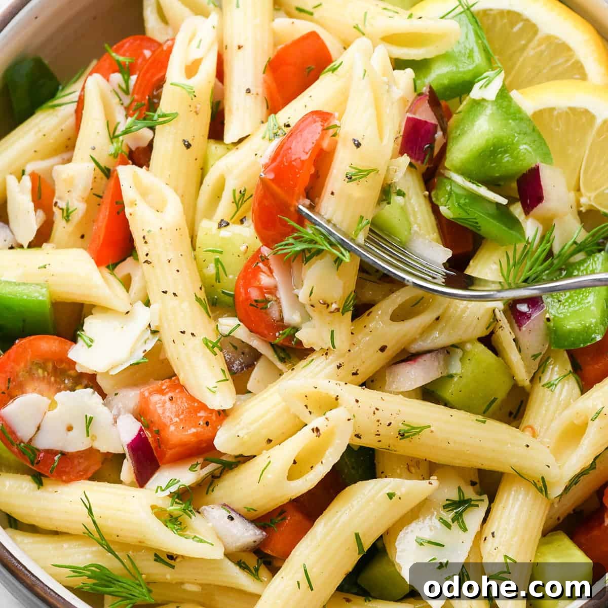 Zesty Lemon Pasta Salad with Fresh Herbs and Creamy Dressing 11 a fork taking a bite of this lemon pasta salad there's penne pasta, tomatoes, bell peppers fresh dill and parmesan cheese