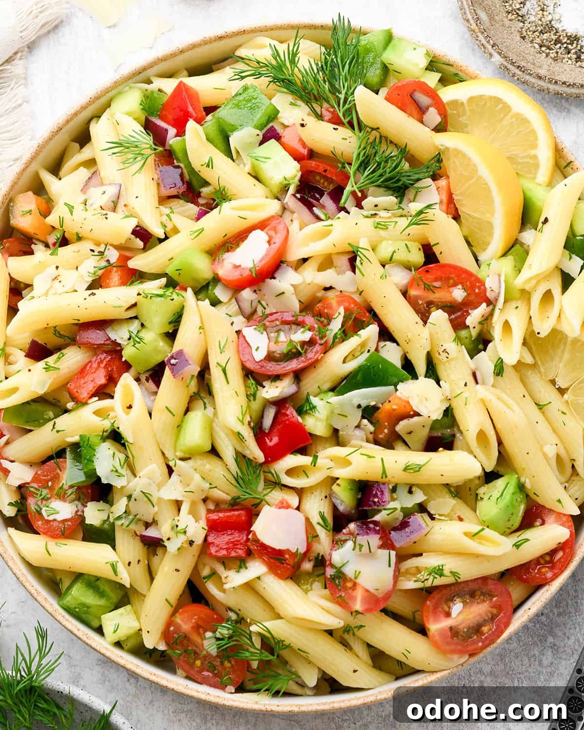 Zesty Lemon Pasta Salad with Fresh Herbs and Creamy Dressing 10 lemon pasta salad with penne pasta, fresh dill, tomatoes, cucumbers and slices of lemon in a large ceramic bowl