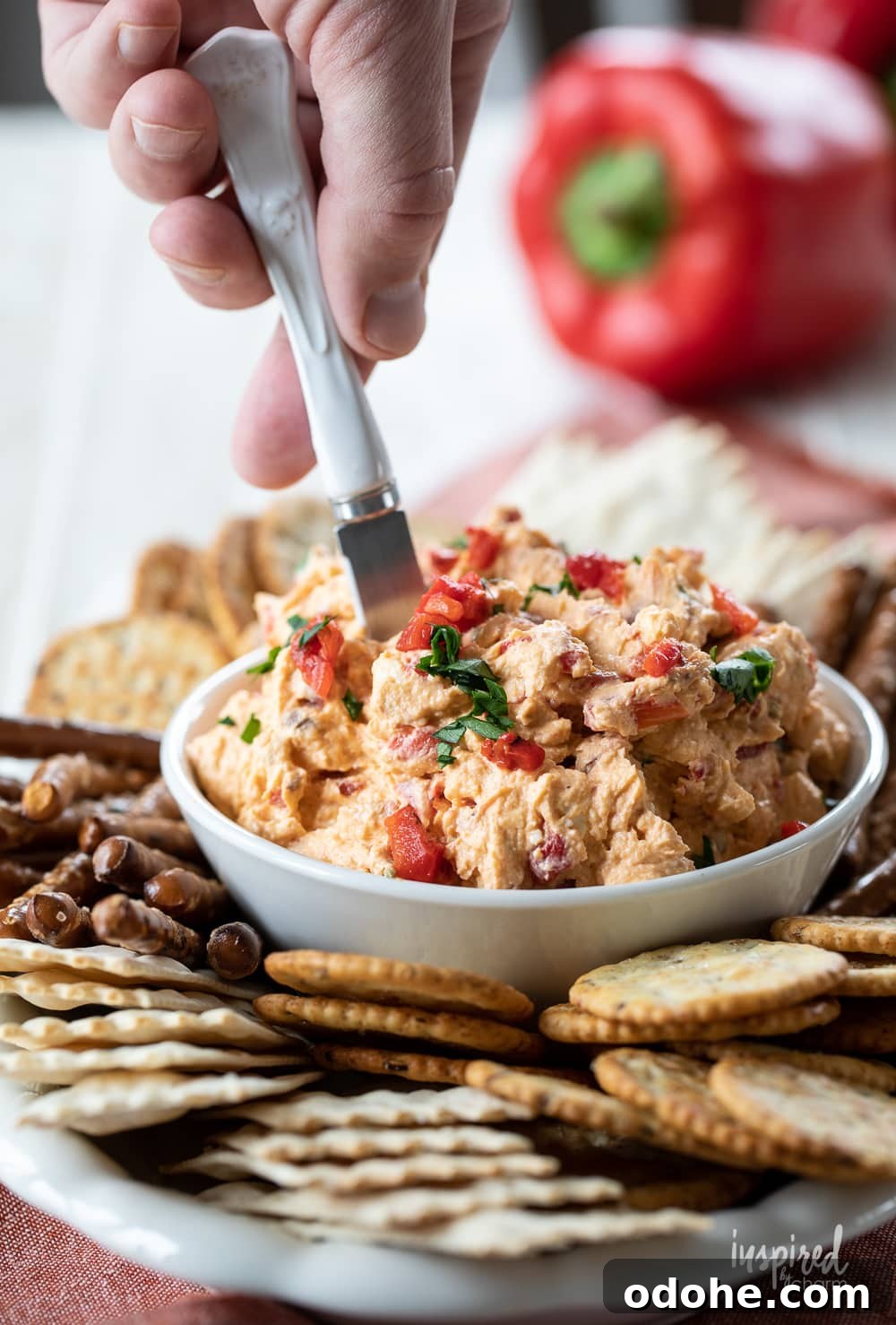 Smoky Roasted Red Pepper Dip Recipe 4 hand serving roasted red pepper dip in a bowl.
