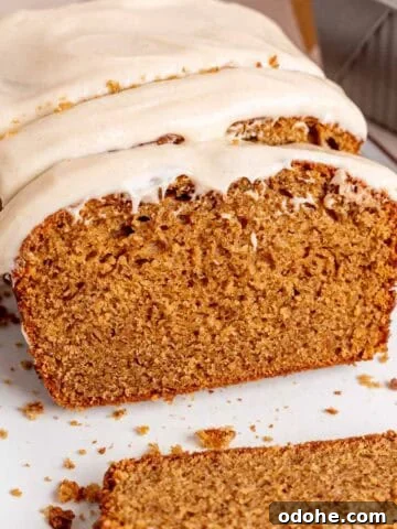 A loaf of spice cake with brown butter cream cheese frosting cut into slices.