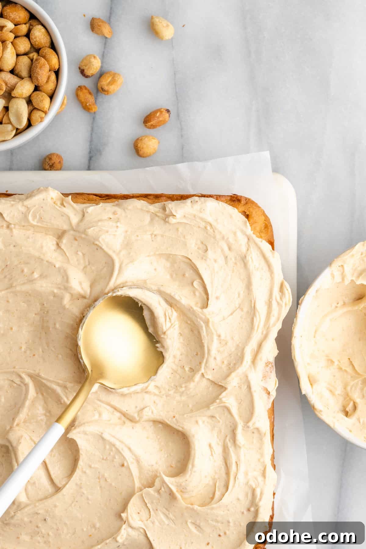 This delicious vegan peanut butter cake recipe is quick and easy to make, bursting with flavor, and the perfect treat with coffee or ice cream Spreading frosting on peanut butter cake