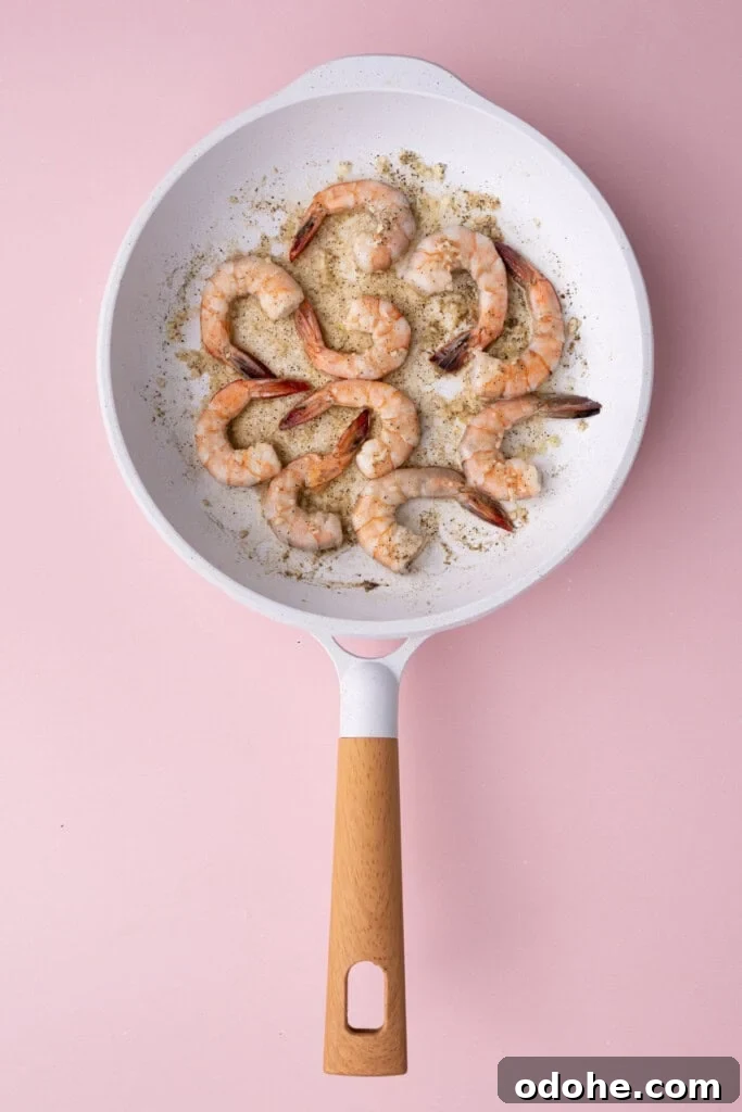 Creamy One-Pan Shrimp Scampi Recipe for Quick Weeknight Dinners 9 Flipping shrimp cooking in a pan with garlic, salt, pepper, and lemon juice.