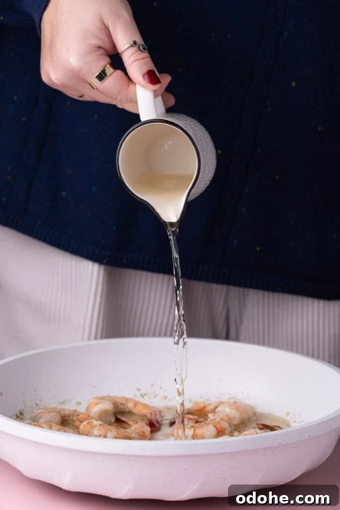 Creamy One-Pan Shrimp Scampi Recipe for Quick Weeknight Dinners 10 Adding white wine to pan with garlic butter shrimp.